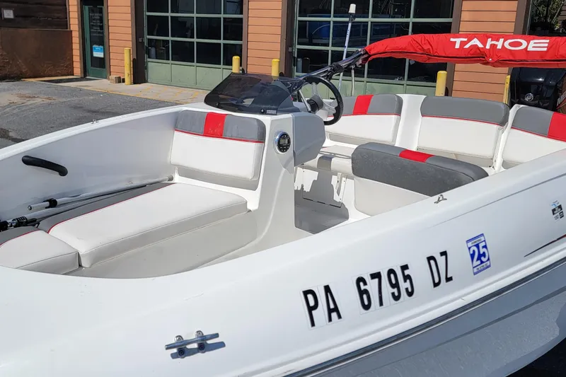 Slide: The Image of 2021 Tahoe T16 boat with red and gray seating, docked near a building. - 5