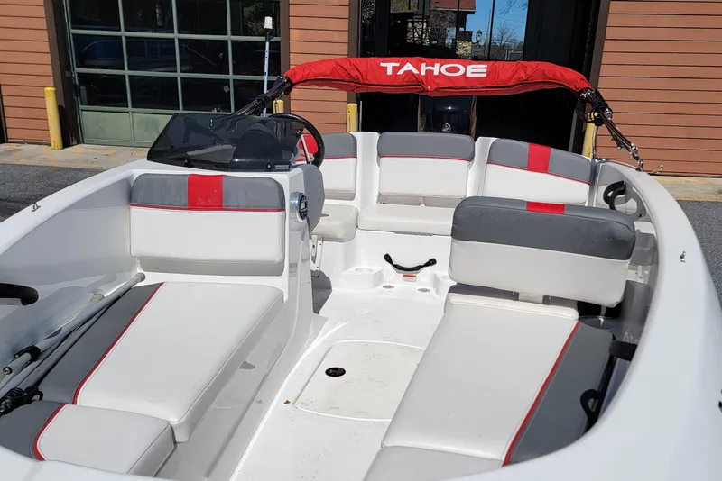 Slide: The Image of 2021 Tahoe T16 boat interior with red and gray seating, parked outdoors. - 6