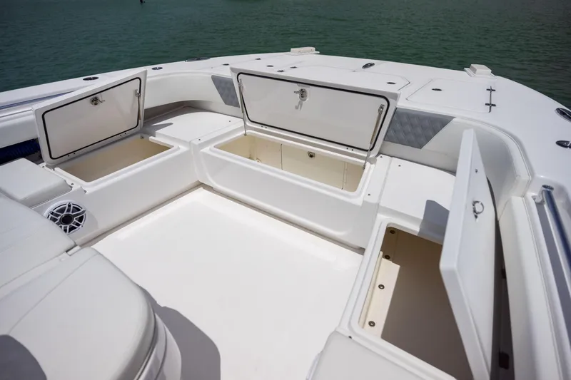 Slide: The Image of 2023 Invincible 37 Catamaran with open storage compartments on deck, near water. - 13
