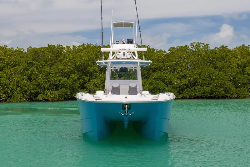 Slide: The Image of 2023 Invincible 37 Catamaran in turquoise water, surrounded by lush greenery. - 4