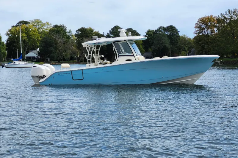 The Image of 2019 Cobia 344 Center Console boat on calm water, surrounded by trees. - 0