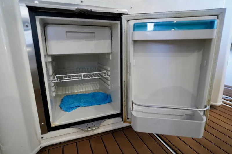 Slide: The Image of Open refrigerator on 2019 Cobia 344 Center Console boat, showing interior shelves and blue cloth. - 10
