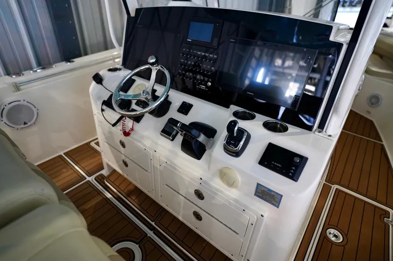 Slide: The Image of 2019 Cobia 344 Center Console boat helm with advanced navigation controls and teak flooring. - 17
