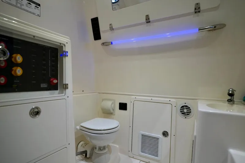 Slide: The Image of Interior of 2019 Cobia 344 Center Console boat featuring a compact marine bathroom. - 29
