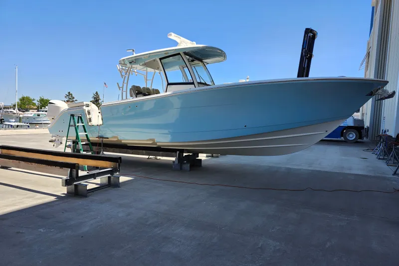 Slide: The Image of 2019 Cobia 344 Center Console boat on dry dock, light blue hull, sunny day. - 4