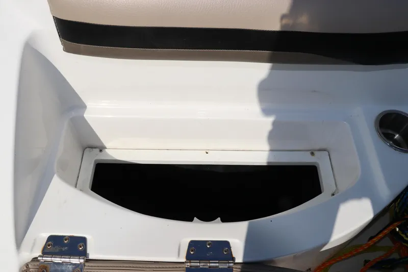Slide: The Image of 2016 Hurricane SunDeck 2486 OB boat storage compartment with beige seating and cup holder. - 10