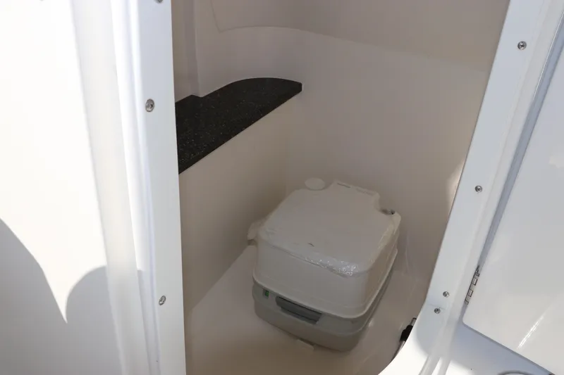 Slide: The Image of 2016 Hurricane SunDeck 2486 OB boat interior with portable toilet and storage space. - 18