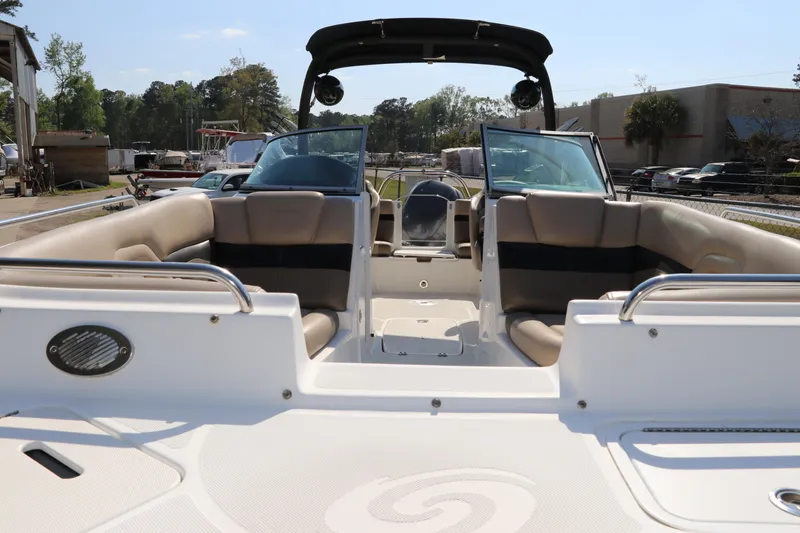 Slide: The Image of 2016 Hurricane SunDeck 2486 OB boat interior with seating and windshield, docked outdoors. - 2