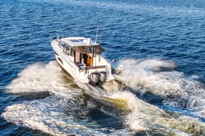 Slide: The Image of 2021 Jeanneau NC 1095 cruising on open water, creating a dynamic wake. - 12