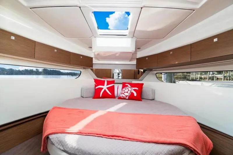 Slide: The Image of 2021 Jeanneau NC 1095 cabin interior with skylight, round bed, and decorative pillows. - 27
