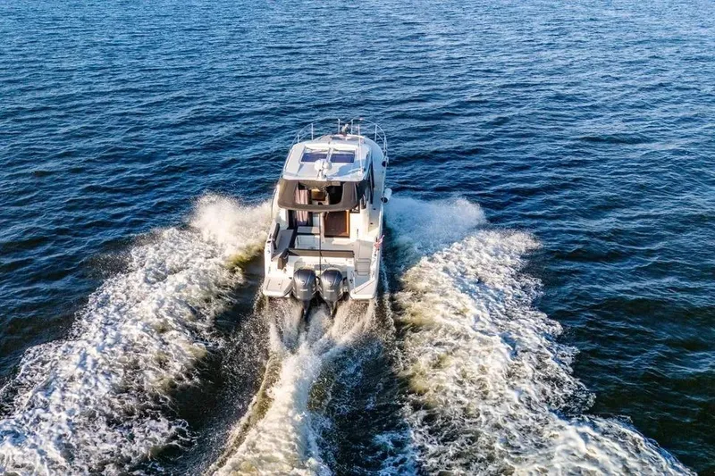 Slide: The Image of 2021 Jeanneau NC 1095 cruising on open water, creating a dynamic wake. - 6