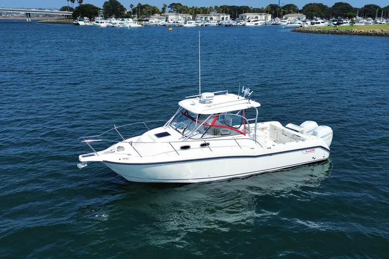 Slide: The Image of 2005 Boston Whaler 305 Conquest boat on calm blue water near marina. - 2