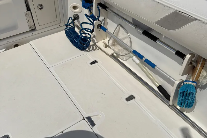 Slide: The Image of 2005 Boston Whaler 305 Conquest deck with fishing gear and coiled blue hose. - 28
