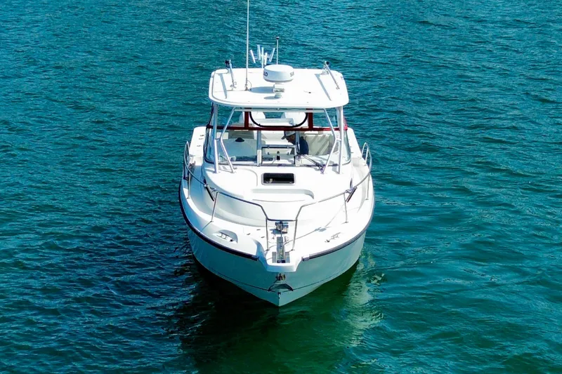 Slide: The Image of 2005 Boston Whaler 305 Conquest boat on clear blue water, front view. - 4