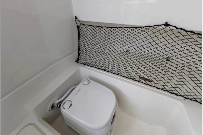 Slide: The Image of 2019 Sea Ray SDX 250 Outboard boat interior with portable toilet and storage net. - 2