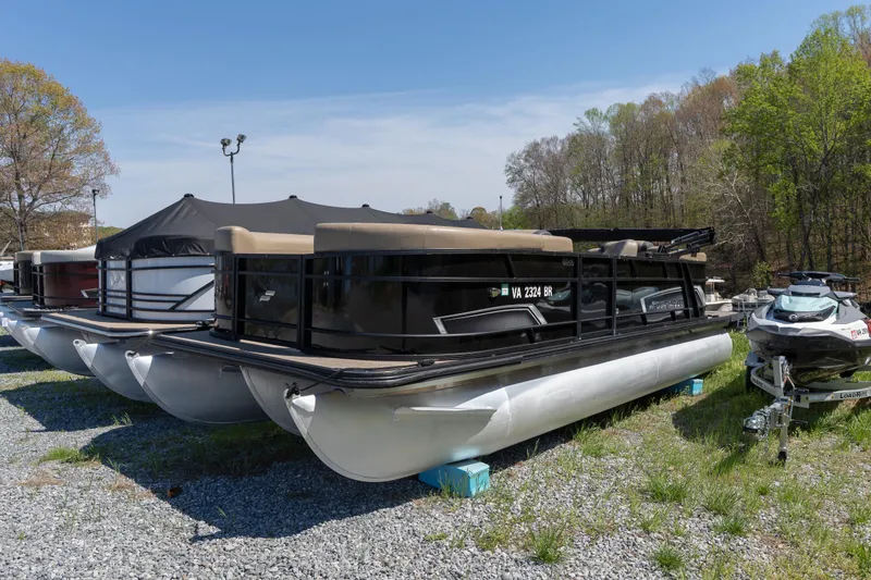 The Image of 2025 Starcraft EXS 3 pontoon boat parked on gravel lot with trees in background. - 0