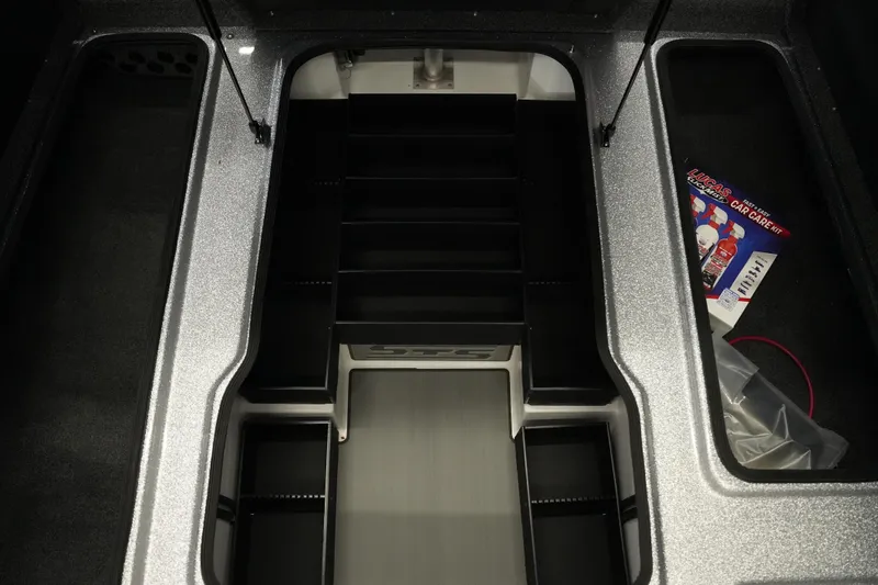 Slide: The Image of 2026 Bass Cat Lynx STS boat storage compartment with organized shelves and car care kit. - 24