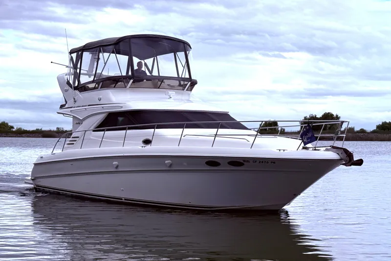 Slide: The Image of 1999 Sea Ray 400 Sedan Bridge yacht cruising on calm waters under cloudy skies. - 1