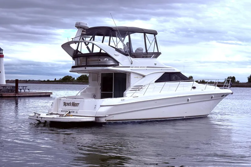 Slide: The Image of 1999 Sea Ray 400 Sedan Bridge yacht docked near a lighthouse under cloudy skies. - 10