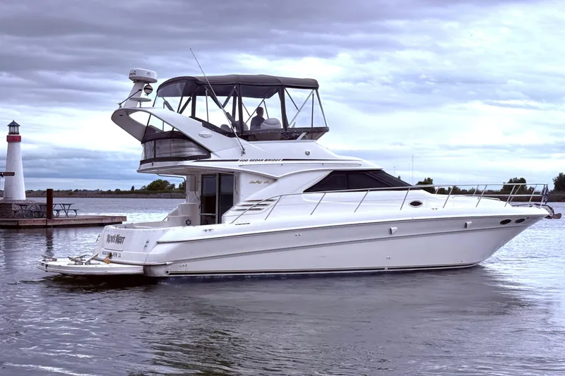 Slide: The Image of 1999 Sea Ray 400 Sedan Bridge yacht docked near a lighthouse under cloudy skies. - 11