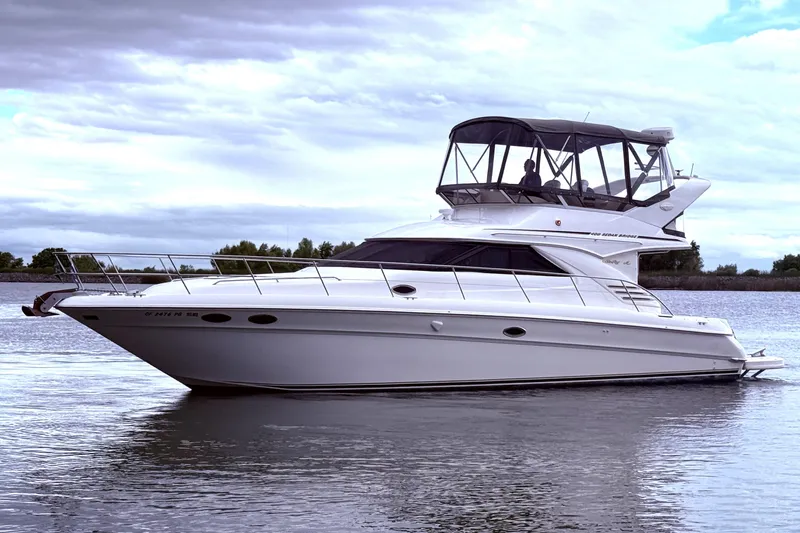 Slide: The Image of 1999 Sea Ray 400 Sedan Bridge yacht on calm water under cloudy sky. - 12