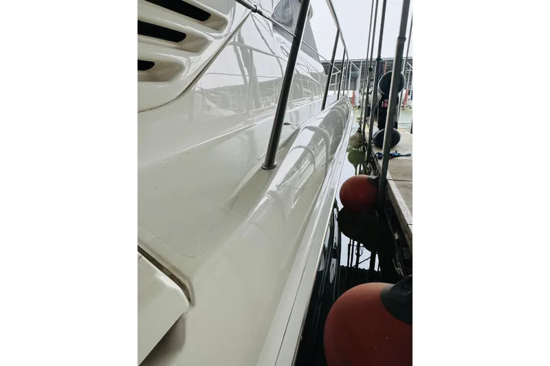 Slide: The Image of 1999 Sea Ray 400 Sedan Bridge yacht docked, showcasing sleek white exterior and railings. - 13