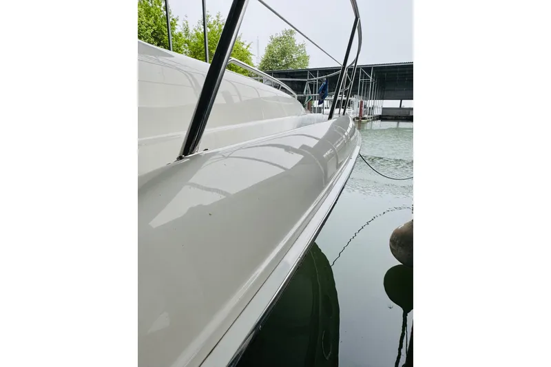 Slide: The Image of 1999 Sea Ray 400 Sedan Bridge yacht docked, showcasing sleek white hull and railing. - 14