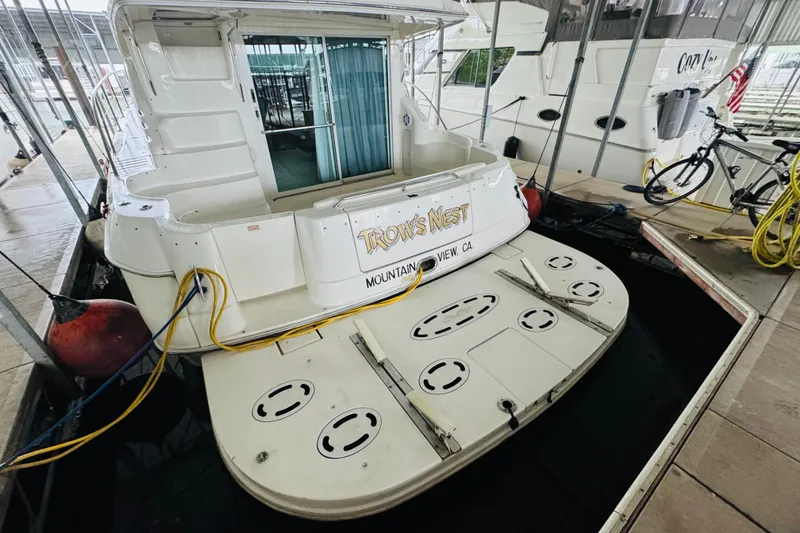 Slide: The Image of 1999 Sea Ray 400 Sedan Bridge docked, rear view with swim platform and boat name visible. - 17