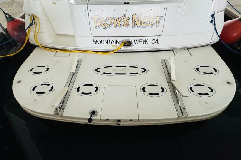 Slide: The Image of 1999 Sea Ray 400 Sedan Bridge boat docked, featuring swim platform and "Trow's Nest" nameplate. - 19