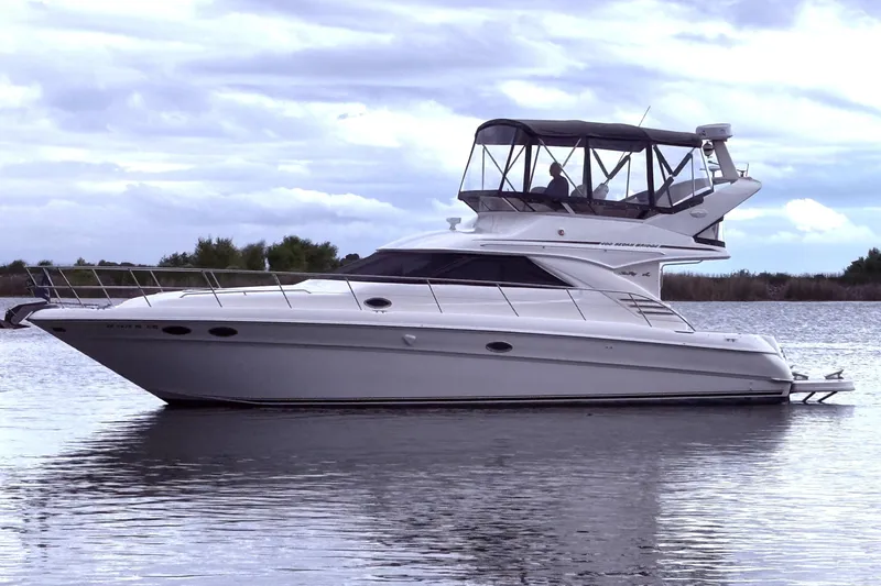 Slide: The Image of 1999 Sea Ray 400 Sedan Bridge yacht on calm water under cloudy sky. - 2