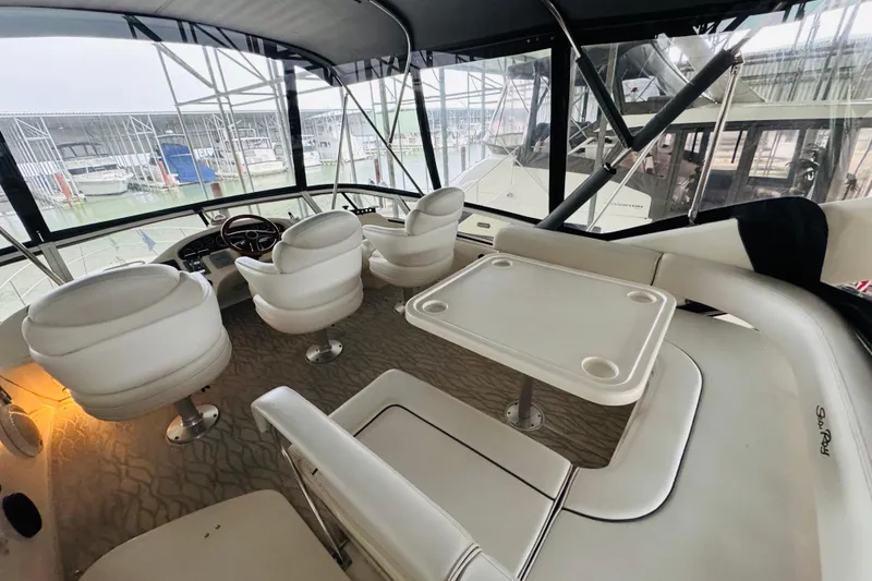 Slide: The Image of 1999 Sea Ray 400 Sedan Bridge interior with helm, seating, and table in marina setting. - 26