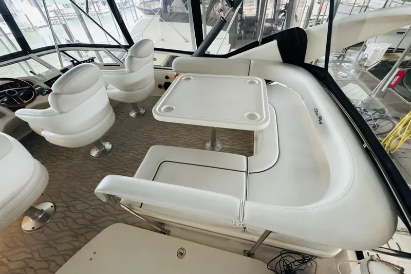 Slide: The Image of 1999 Sea Ray 400 Sedan Bridge interior with white seating and table on deck. - 27
