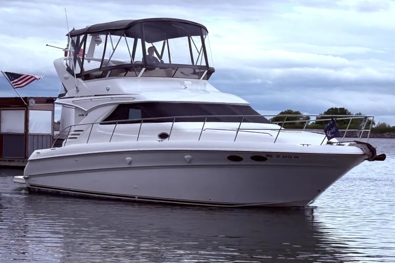 Slide: The Image of 1999 Sea Ray 400 Sedan Bridge yacht docked on calm water under cloudy skies. - 3