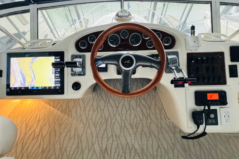 Slide: The Image of 1999 Sea Ray 400 Sedan Bridge helm with navigation display and wood-accented steering wheel. - 37