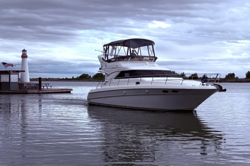 Slide: The Image of 1999 Sea Ray 400 Sedan Bridge yacht near a lighthouse on a cloudy day. - 4