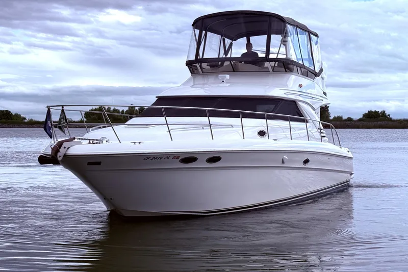 Slide: The Image of 1999 Sea Ray 400 Sedan Bridge yacht cruising on calm waters under cloudy skies. - 5
