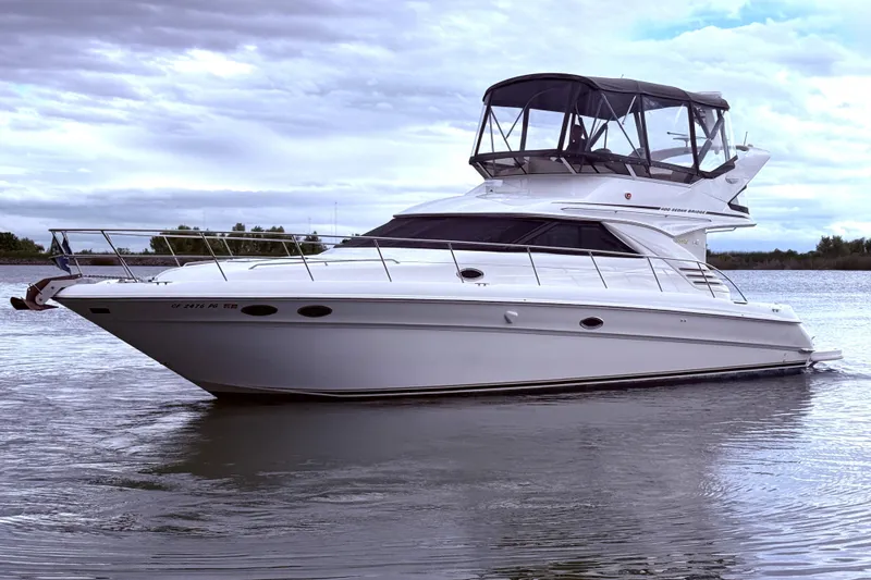 Slide: The Image of 1999 Sea Ray 400 Sedan Bridge yacht on calm water under cloudy skies. - 6