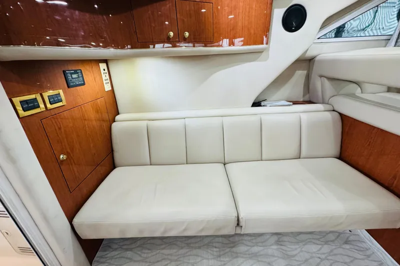Slide: The Image of 1999 Sea Ray 400 Sedan Bridge interior with beige leather seating and wooden cabinetry. - 65