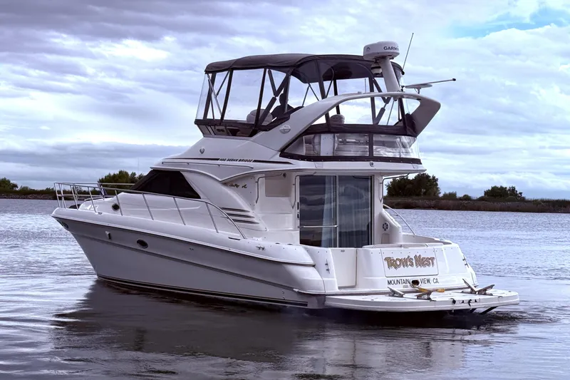 Slide: The Image of 1999 Sea Ray 400 Sedan Bridge yacht on calm water under cloudy sky. - 7