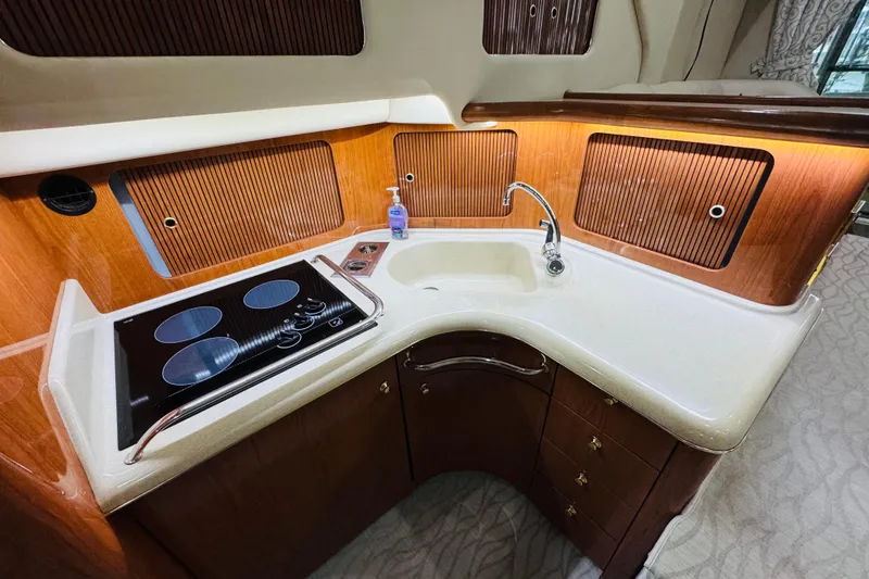 Slide: The Image of 1999 Sea Ray 400 Sedan Bridge kitchen with stove, sink, and wooden cabinetry. - 72