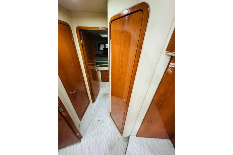 Slide: The Image of Interior hallway of a 1999 Sea Ray 400 Sedan Bridge with wooden doors and patterned flooring. - 75
