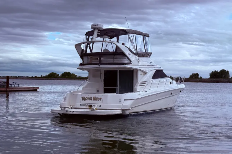 Slide: The Image of 1999 Sea Ray 400 Sedan Bridge yacht on a cloudy day, docked on calm water. - 9