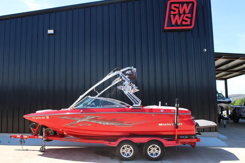 Slide: The Image of 2007 MasterCraft X2 boat in red on trailer, parked outside SWWS building. - 1
