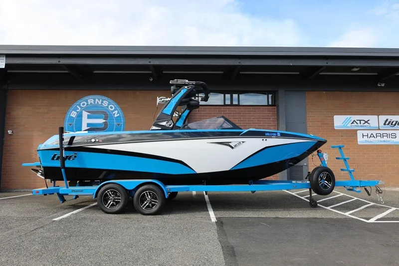 Slide: The Image of 2022 Tigé Z3 boat on trailer, blue and white design, parked outside dealership. - 2