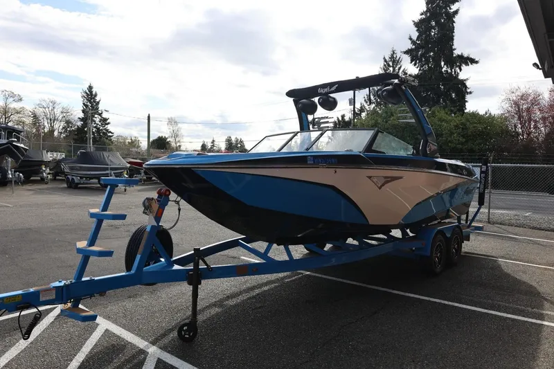 Slide: The Image of 2022 Tigé Z3 boat on trailer, blue and black design, parked outdoors. - 7