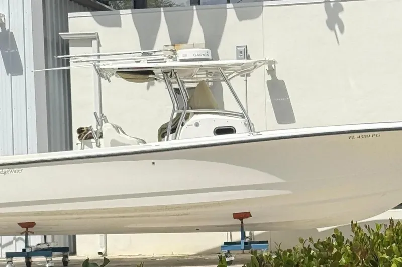 Slide: The Image of 2010 Edgewater 318CC boat on stands, white exterior, parked near a building. - 2