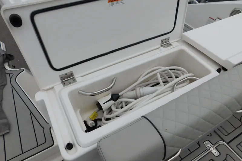 Slide: The Image of Storage compartment on 2023 Pursuit OS 325 Offshore boat with coiled hose inside. - 11
