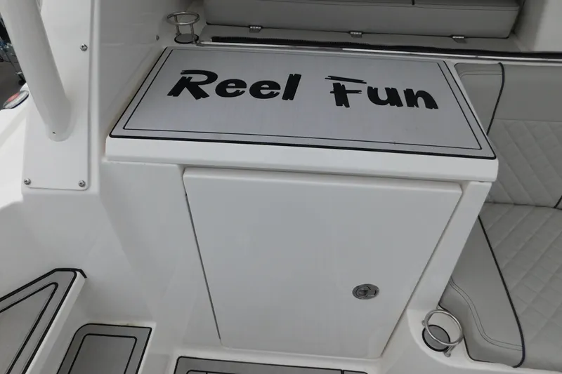 Slide: The Image of 2023 Pursuit OS 325 Offshore boat interior with "Reel Fun" text on a compartment. - 13