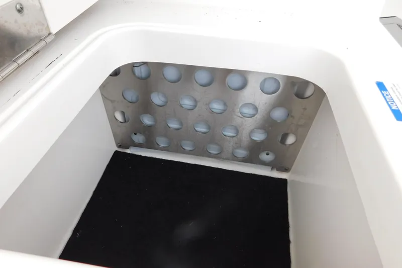 Slide: The Image of Storage compartment in 2023 Pursuit OS 325 Offshore boat, featuring a perforated metal panel. - 17