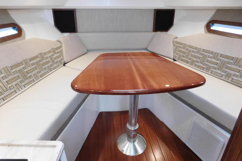 Slide: The Image of 2023 Pursuit OS 325 Offshore cabin interior with wooden table and cushioned seating. - 42
